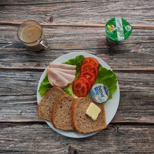 Zdjęcie przedstawia Dietę z ograniczeniem łatwoprzyswajalnych węglowodanów: Chleb Graham Masło extra Kawa zbożowa z mlekiem Serek twarogowy termizowany smak śmietankowy Kefir Pomidor Szynkowa dębowa drobiowa kiełbasa grubo rozdrobniona Sałata zielona